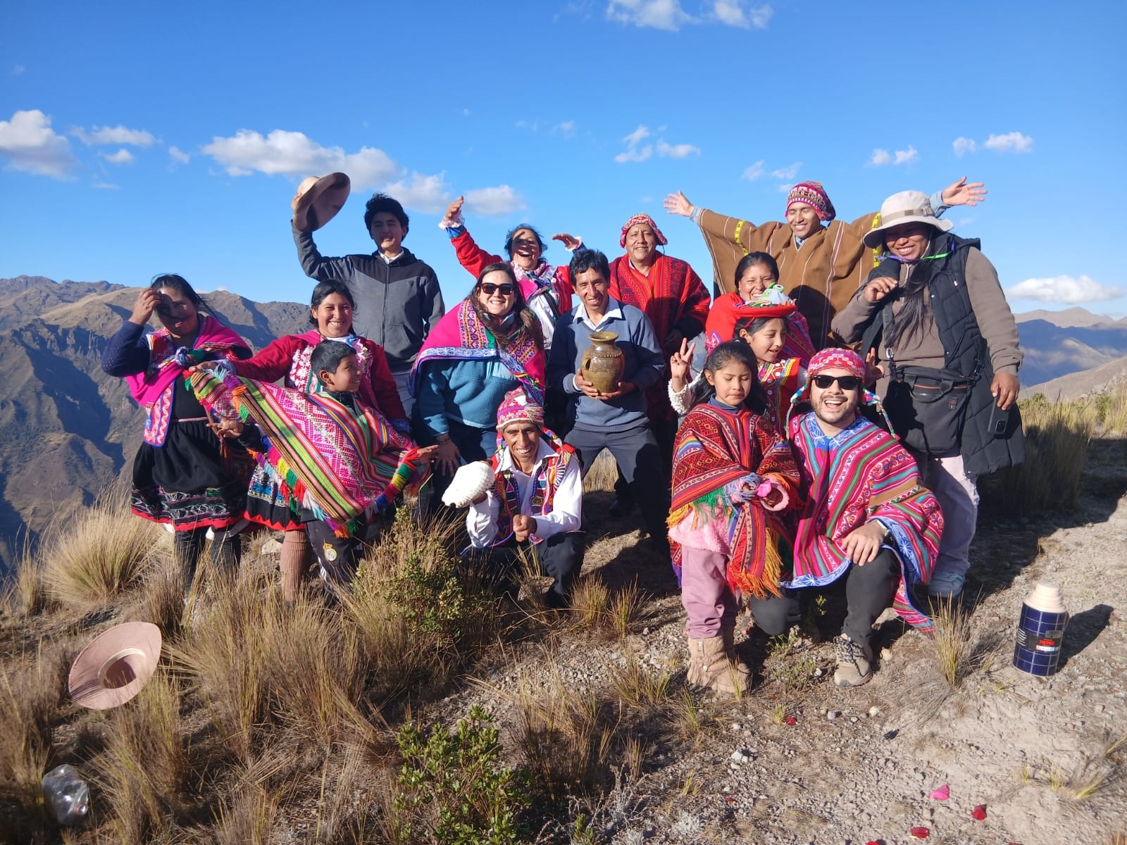 Grupo completo de viajeros y familias de la comunidad de Kallarayan celebrando en la cumbre del Valle Sagrado, cerca de Cusco, con una ofrenda a la Pachamama